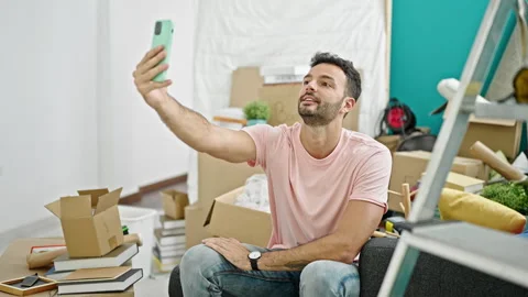 Young hispanic man having video call sitting on sofa at new home Stock Footage 247378856