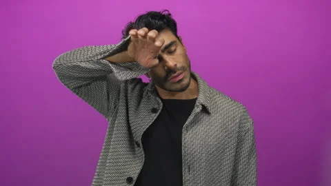 Young hispanic man in herringbone jacket wipes sweat from forehead over viv.. Stock Footage 314629409