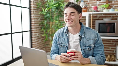 Young hispanic man holding cup of coffee speaking at dinning room Video stock 243481664