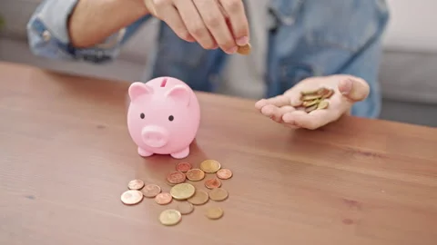 Young hispanic man inserting coins on piggy bank sitting on floor at home Video stock 243478867