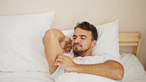 Young hispanic man lying on bed scratching arm at bedroom Video stock 246126981