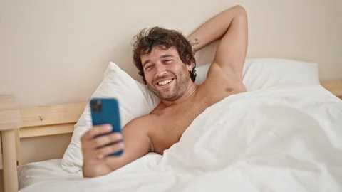 Young hispanic man lying on bed shirtless having video call at bedroom Video stock 246132408