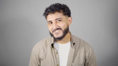 Young hispanic man making different facial expressions on gray background Stock Footage 314785397