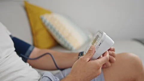 Young hispanic man measuring pulse using tensiometer at home Stock Footage 243490030