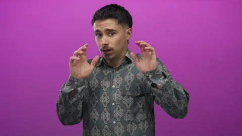 Young hispanic man in patterned shirt looks scared against an isolated pink.. Stock Footage 308533499