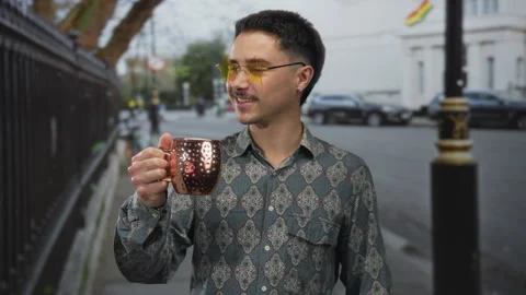 Young hispanic man with a patterned shirt and yellow glasses holds a copper.. Stock Footage 309119914