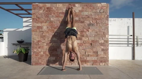 Young hispanic man practices handstand against wall - slow motion Stock Footage 163471926