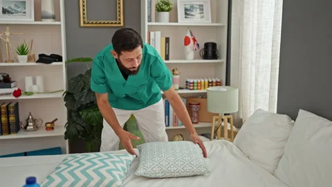 Young hispanic man professional cleaner make bed at bedroom Vidéo 253051737