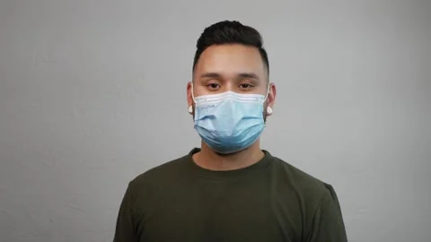 Young Hispanic Man Putting On His Face Mask with Neutral Expression Stock Footage 173346996