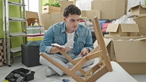Young hispanic man reading instructions to repair chair at new home Video stock 243481622