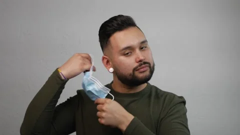 Young Hispanic Man Removing His Mask with Neutral Expression. Stock Footage 173346995
