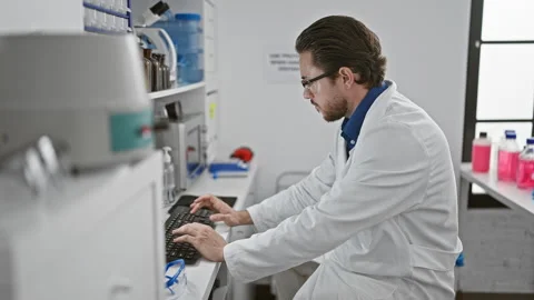 Young hispanic man scientist using computer taking glasses off stretching a.. 動画素材 257096492