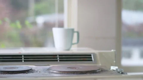 Young hispanic man sets tea kettle on stove and turns burner on Stock Footage 84451935