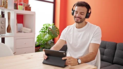 Young hispanic man sitting on table listening to music and dancing at dinni.. Video stock 245039525