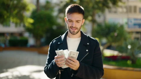Young hispanic man smiling confident counting dollars at park Stock Footage 170655421