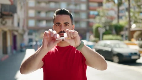 Young hispanic man smiling confident breaking cigarette at street Video stock 172420214