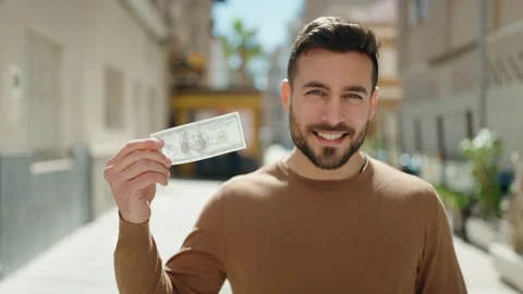 Young hispanic man smiling confident holding dollar at street Video stock 173789073