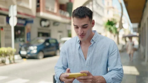 Young hispanic man smiling confident playing video game at street Stock Footage 208883291