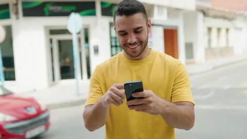 Young hispanic man smiling confident using smartphone at street Stock Footage 220152050
