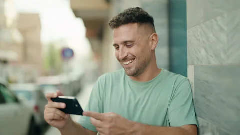 Young hispanic man smiling confident watching video on smartphone at street Video stock 231507148