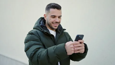 Young hispanic man smiling confident using smartphone over isolated white b.. Video stock 246134083