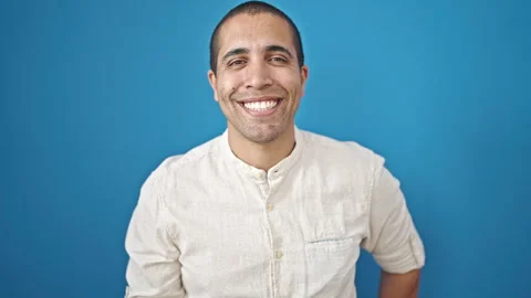 Young hispanic man smiling confident standing over isolated blue background Video stock 247377310