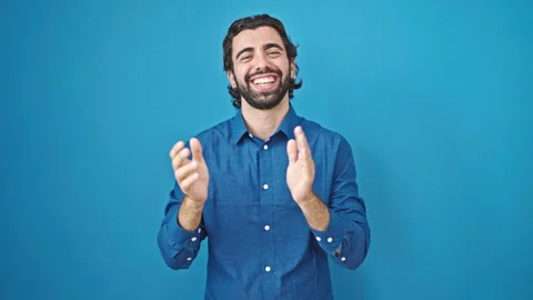 Young hispanic man smiling confident clapping hands over isolated blue back.. Stock Footage 247378302