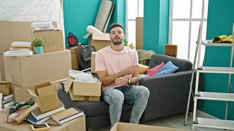 Young hispanic man smiling confident sitting on sofa with arms crossed gest.. Stock Footage 247378842