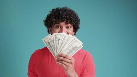 Young hispanic man smiling confident covering mouth with dollars over isolated Stock Footage 261735089