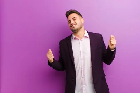 Young hispanic man smiling, feeling carefree, relaxed and happy, dancing and  Stock Photos