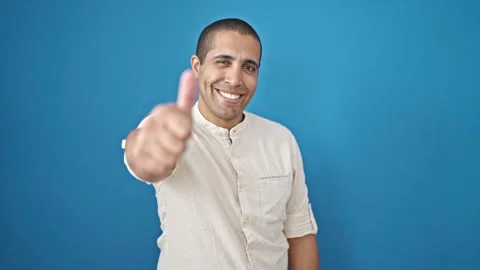 Young hispanic man smiling with thumbs up over isolated blue background Video stock 246124794