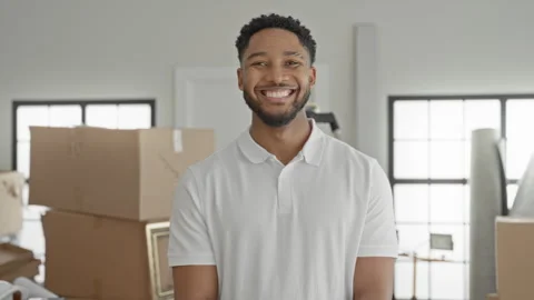 Young hispanic man with stacked cardboard moving boxes and a framed picture.. Stock Footage 337438822