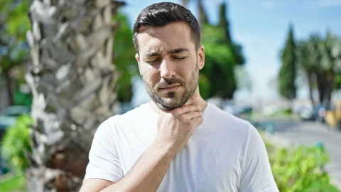 Young hispanic man standing with serious expression being sick at park Stock Footage 243489582