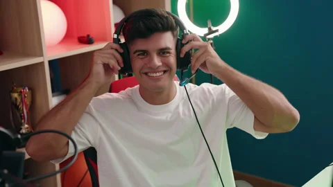 Young hispanic man streamer smiling confident sitting on table at gaming room Stock Footage 205014375