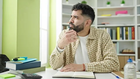 Young hispanic man student reading book with doubt expression at library un.. Video stock 245046867