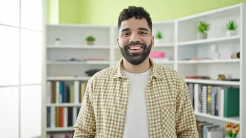 Young hispanic man student smiling confident standing at library university Stock Footage 245046646
