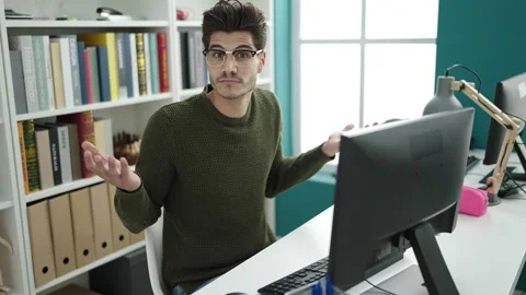 Young hispanic man student using computer doing i dont know expression at l.. Stock Footage 232875977