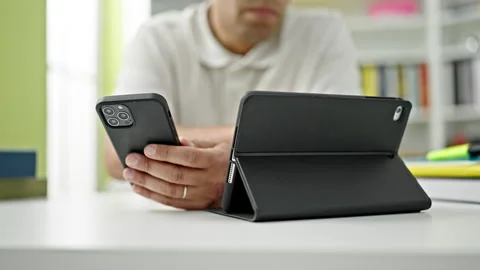 Young hispanic man student using touchpad and smartphone at library universit Video stock 247377363