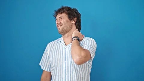 Young hispanic man suffering for cervical pain over isolated blue background Stock Footage 246132475
