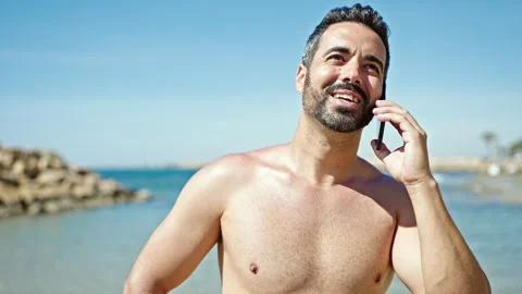 Young hispanic man tourist talking on smartphone standing shirtless at the .. Video stock 245079592
