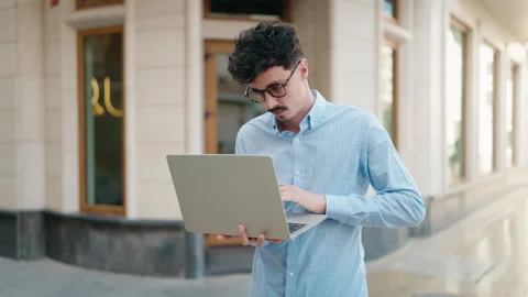 Young hispanic man using laptop at street Stock Footage 171800788