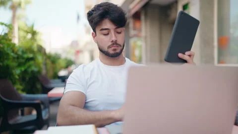 Young hispanic man using laptop and touchpad at coffee shop terrace Video stock 206485267