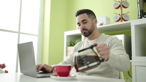 Young hispanic man using laptop drinking coffee at home Video stock 232876202