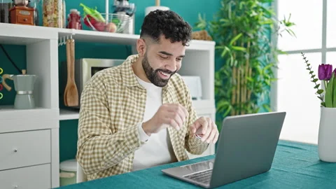 Young hispanic man using laptop with idea expression at dinning room Stock Footage 245046448