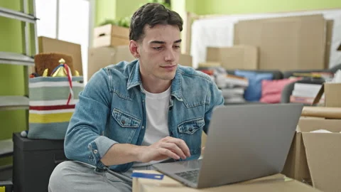 Young hispanic man using laptop and credit card sitting on sofa at new home Video stock 246123529