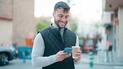 Young hispanic man using smartphone and drinking coffee at street Video stock 170115329
