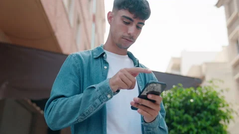 Young hispanic man using smartphone with serious expression at street Video stock 221107642