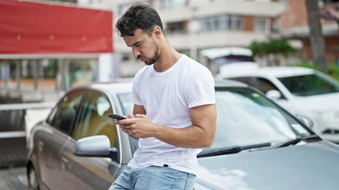 Young hispanic man using smartphone sitting on car at street Video stock 245031906