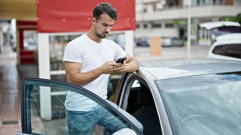 Young hispanic man using smartphone leaning on car at street Video stock 246127452