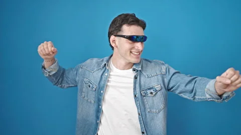 Young hispanic man using virtual reality glasses dancing over isolated blue.. Video stock 243481272